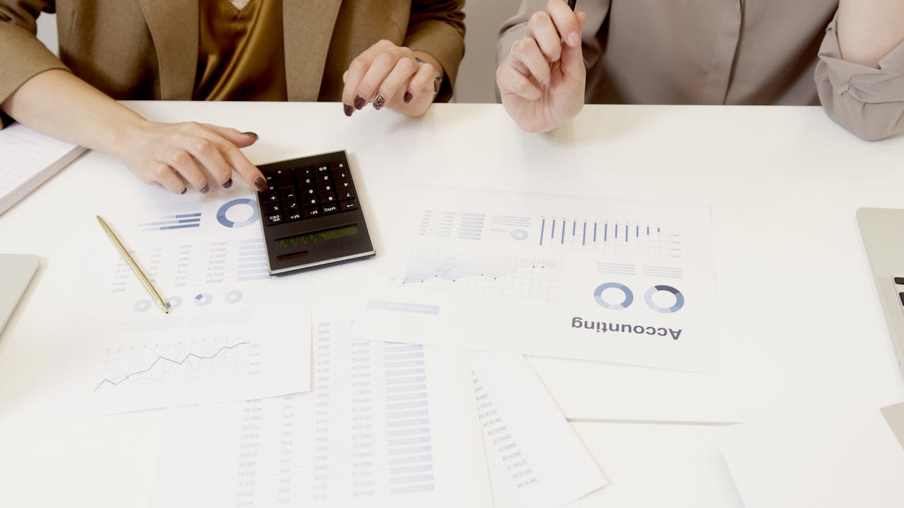 brand-01 Two professionals analyzing financial documents with a calculator.